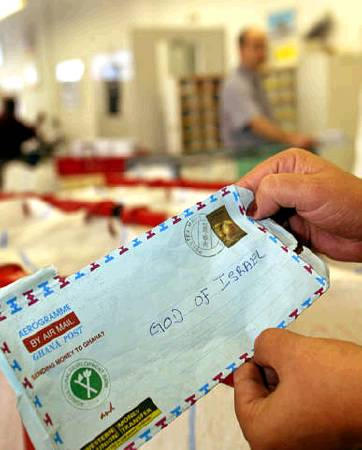 Hundreds of letters written to God arrive in Israel each year, most around Jewish holidays, to be read and taken to the Western Wall in Jerusalem. A post office employee holds one of these letters in a sorting room in an Israeli post office, Jerusalem, October 2, 2003.